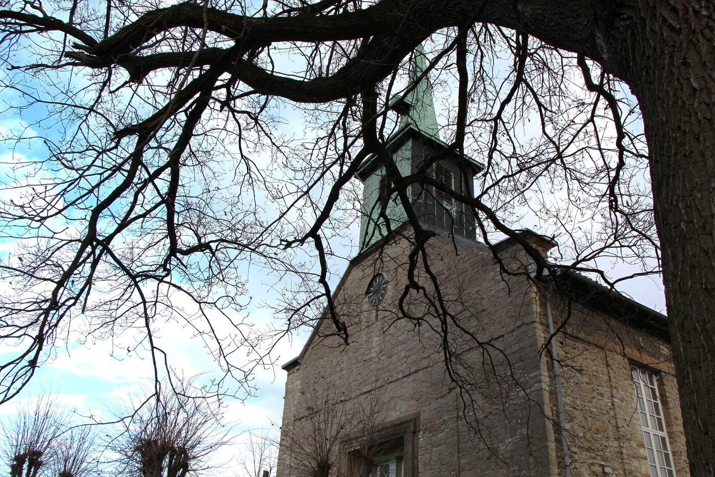 Die Beuchter Kirche im Winter, durch kahle Äste gesehen
